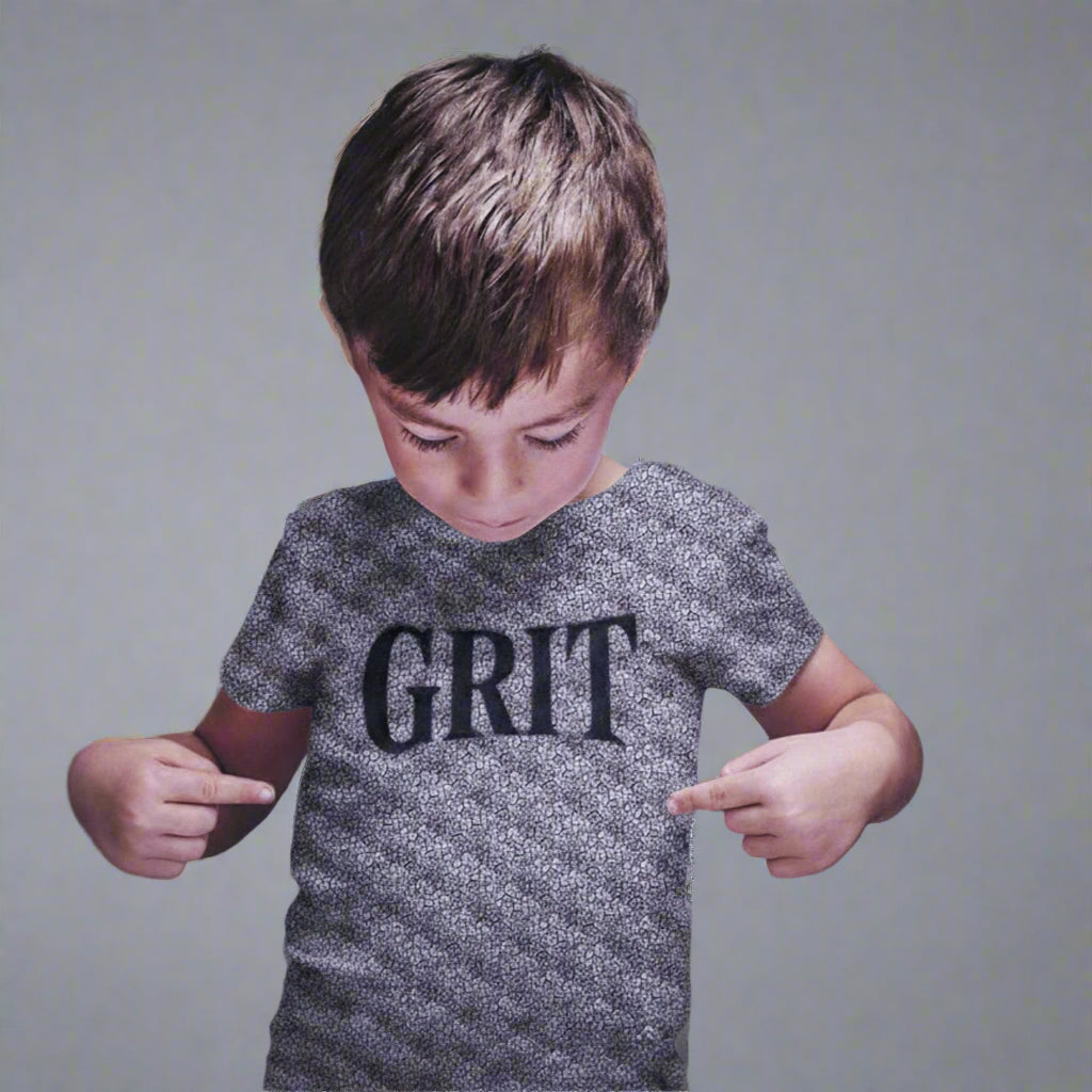 A boy points to a shirt reading "GRIT" an emotional skill celebrated by the boy apparel brand House Panther
