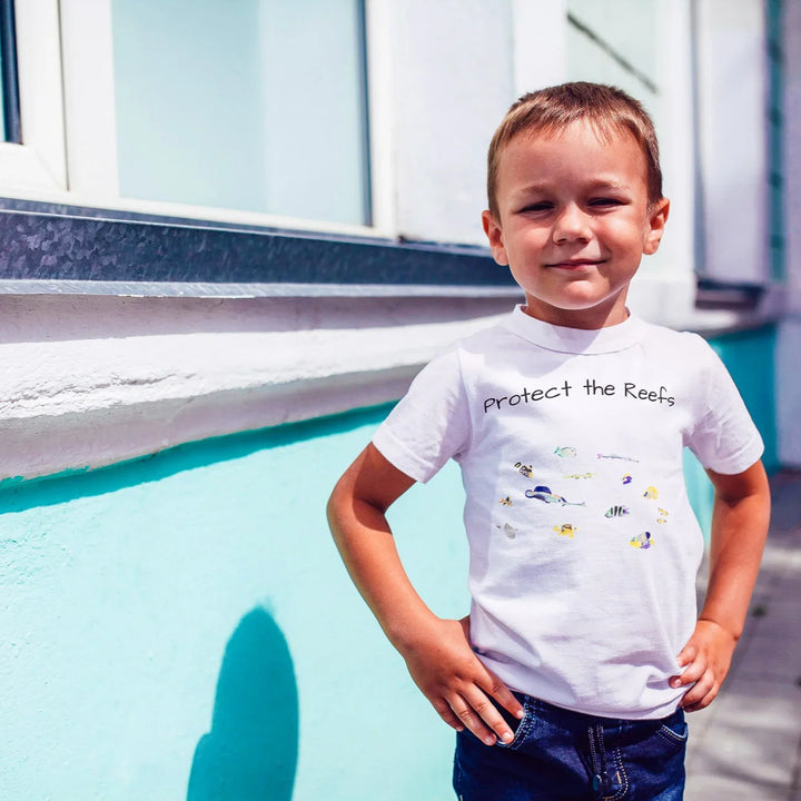Child wearing a 'Protect the Reefs' t-shirt standing by a pool.