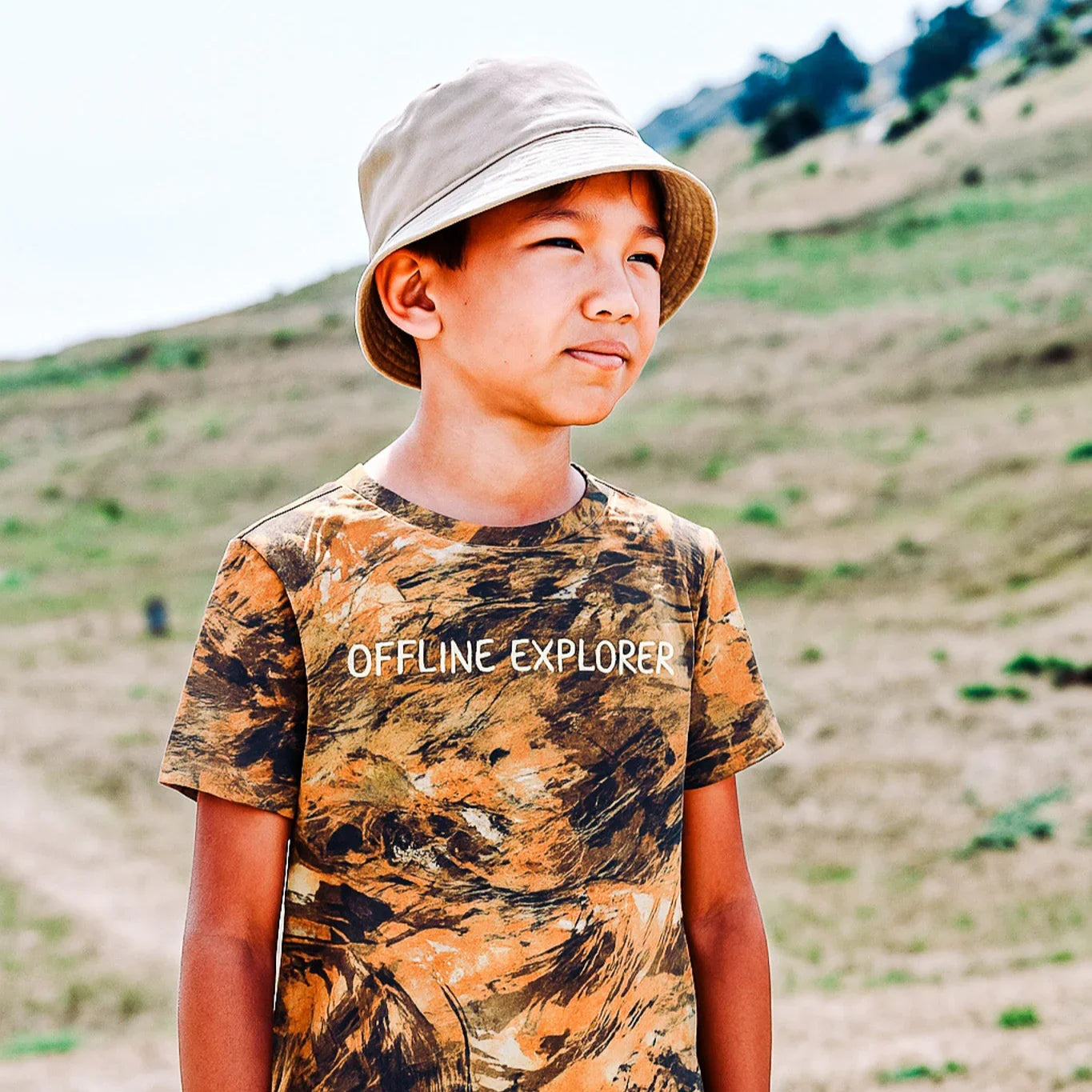 Child wearing a camouflage t-shirt with 'Offline Explorer' text, standing outdoors.