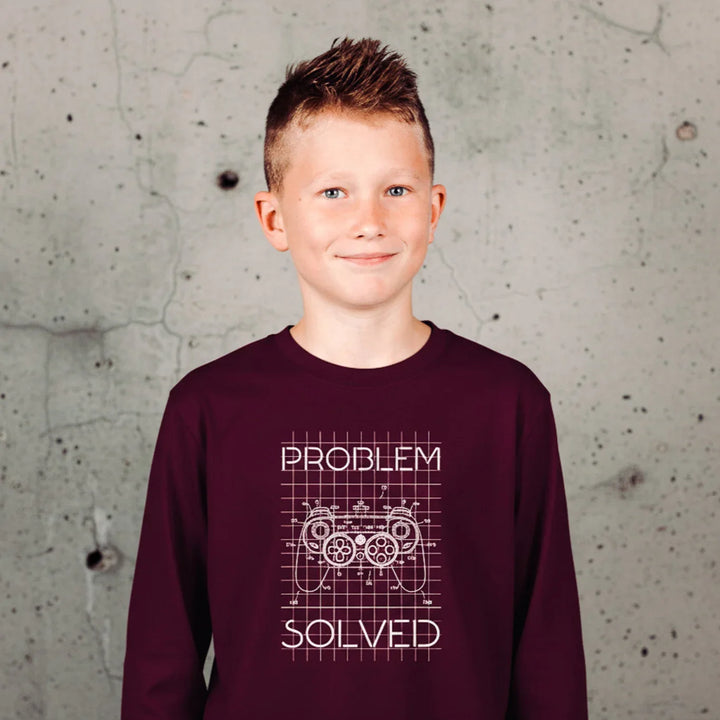 Young boy wearing a maroon sweatshirt with 'Problem Solved' text against a textured wall.