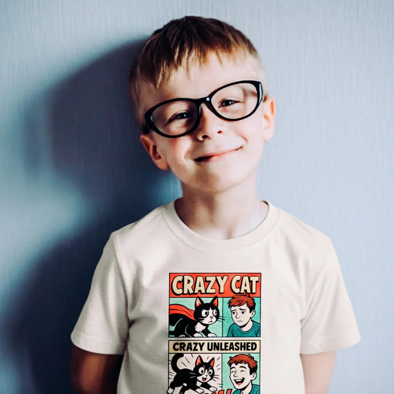 Child wearing a t-shirt with a comic design against a light blue wall