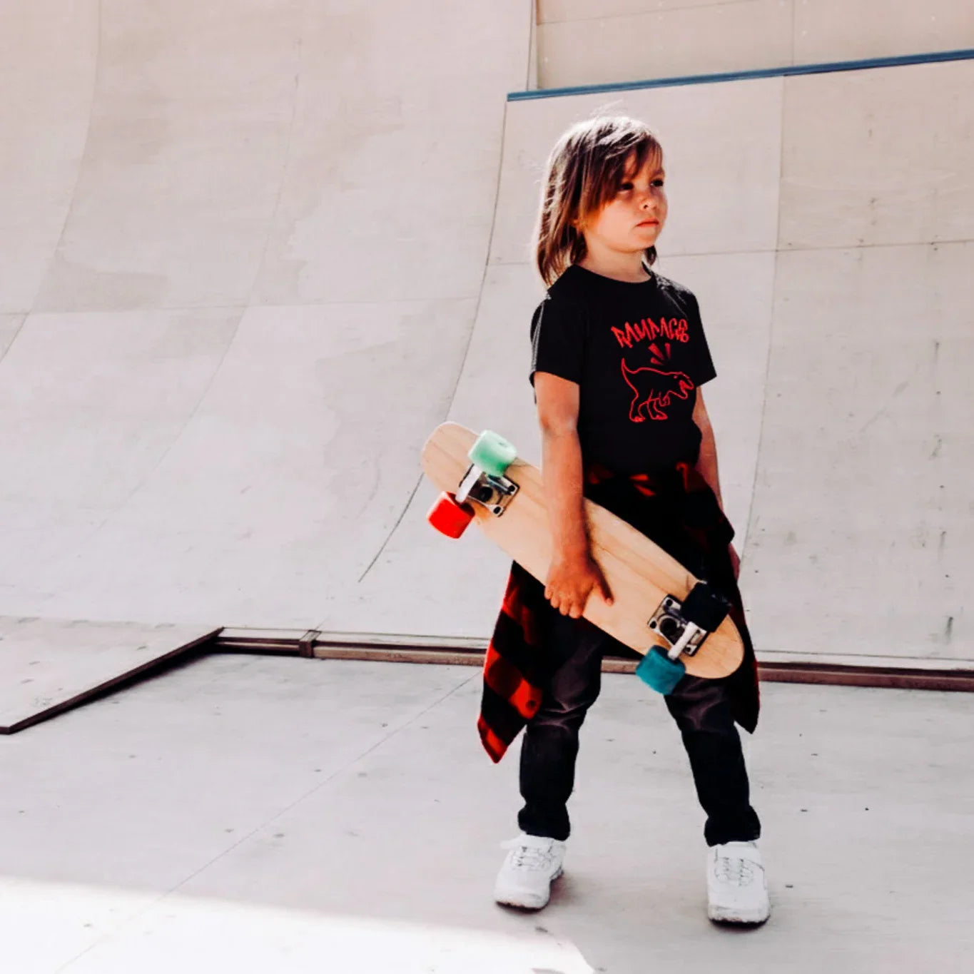 Child holding a skateboard in an indoor skate park