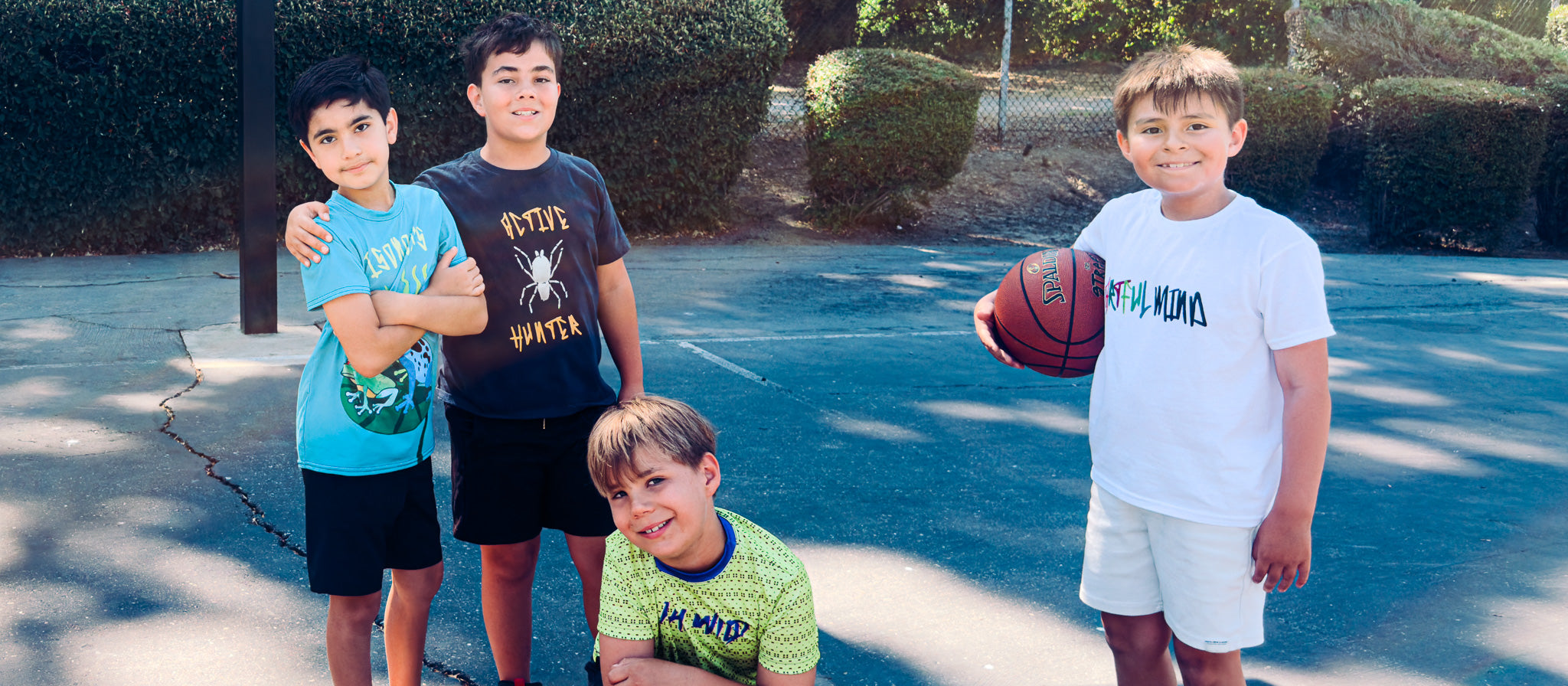 Four boys standing on a basketball court with a ball wearing house panther durable apparel
