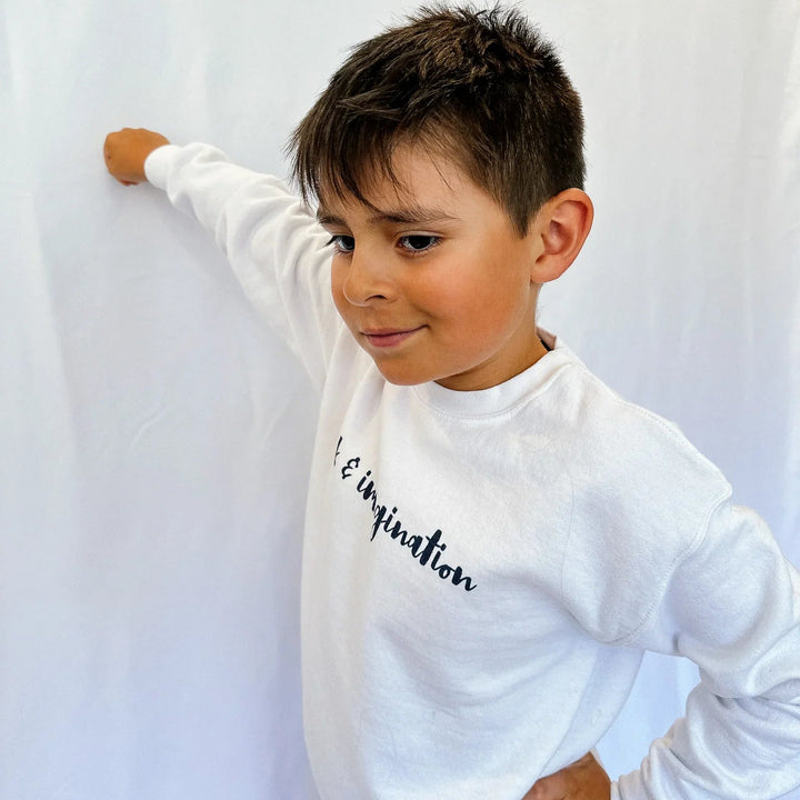 Child wearing a white long-sleeve shirt with text against a white background