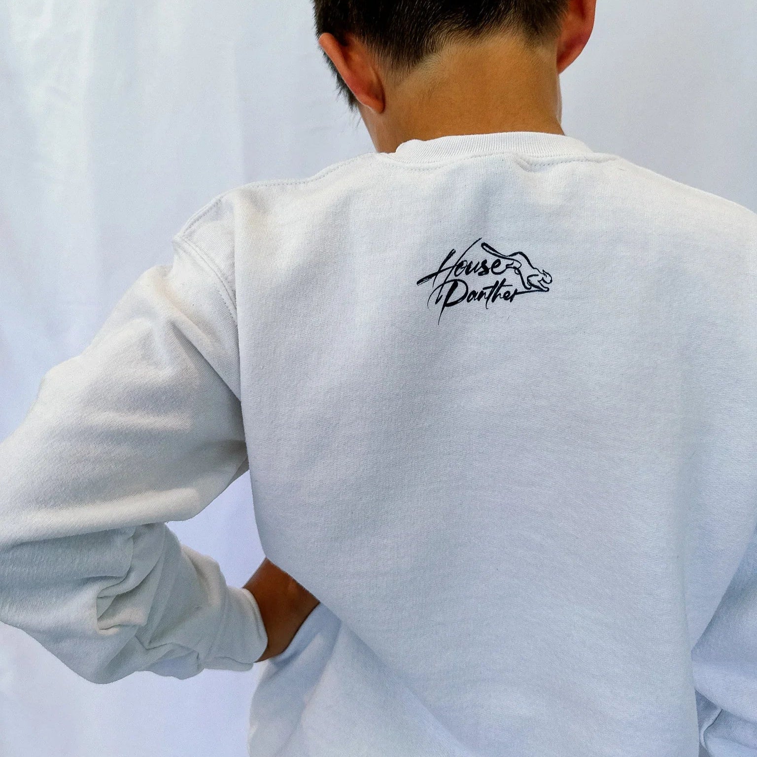 Person wearing a white sweatshirt with a logo on the back against a white background