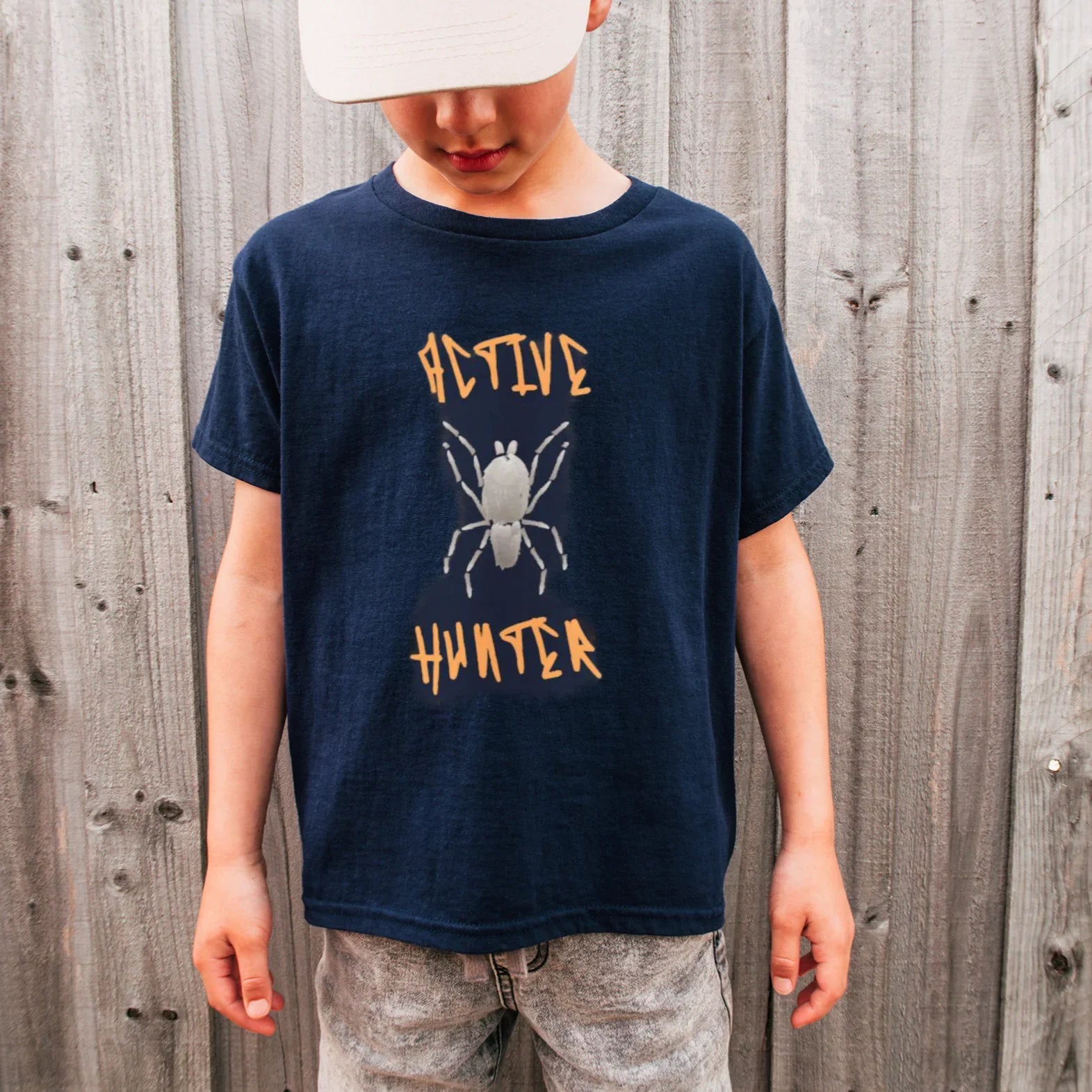 Child wearing a navy blue t-shirt wolf spider, House Panther with 'Active Hunter' graphic against a wooden fence background