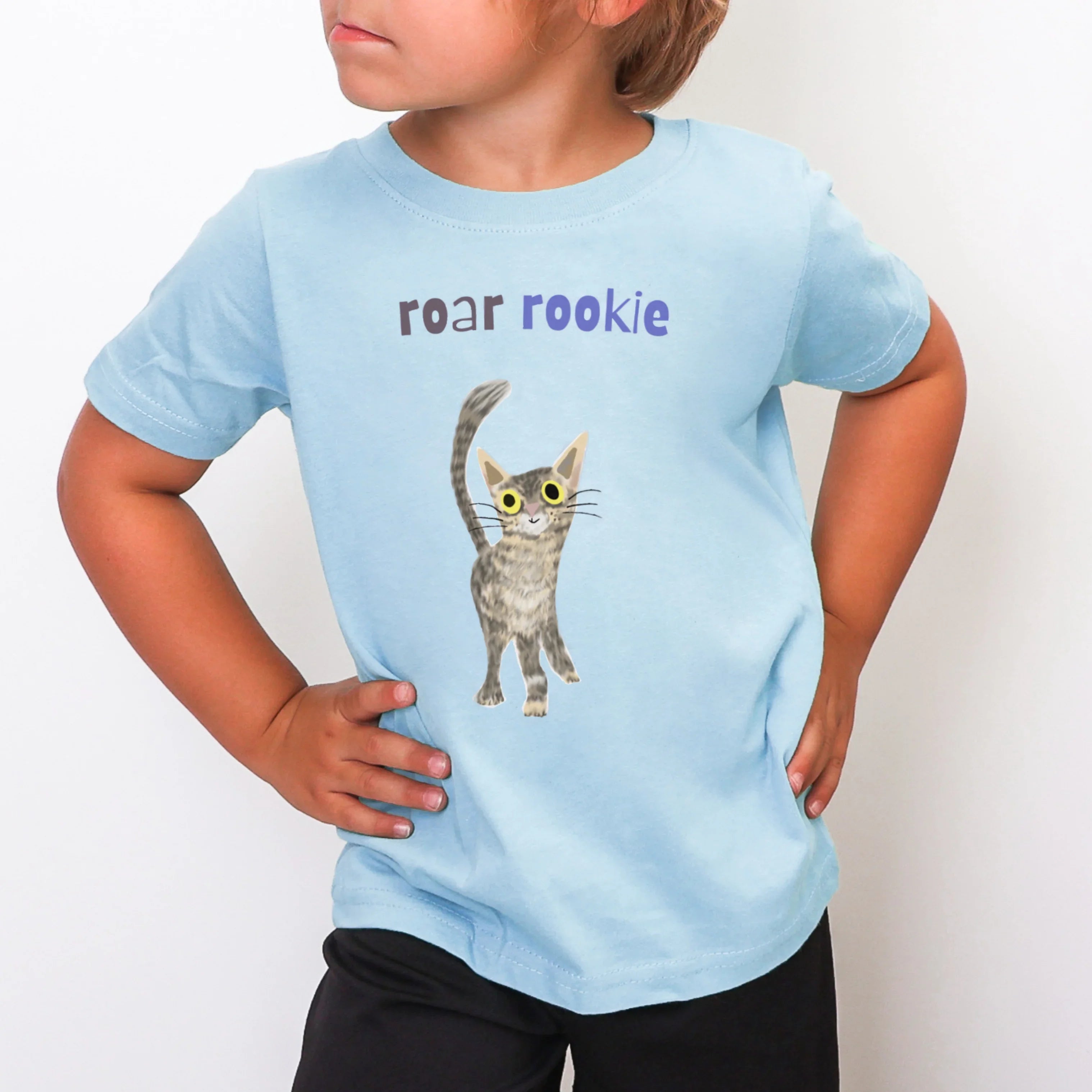 Child wearing a light blue t-shirt with a cat graphic and text on a white background