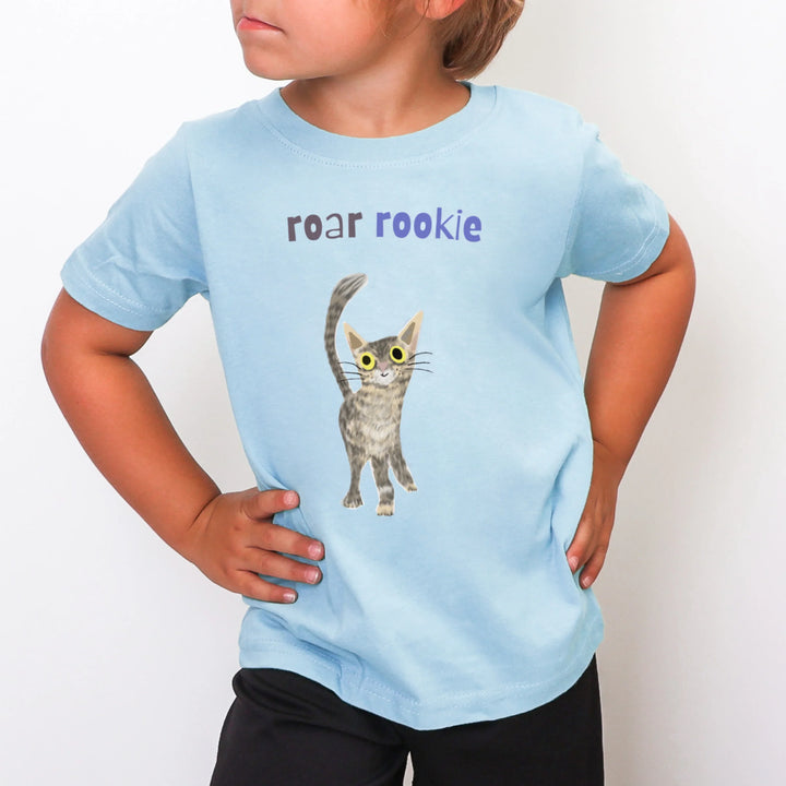 Child wearing a light blue t-shirt with a cat graphic and text on a white background