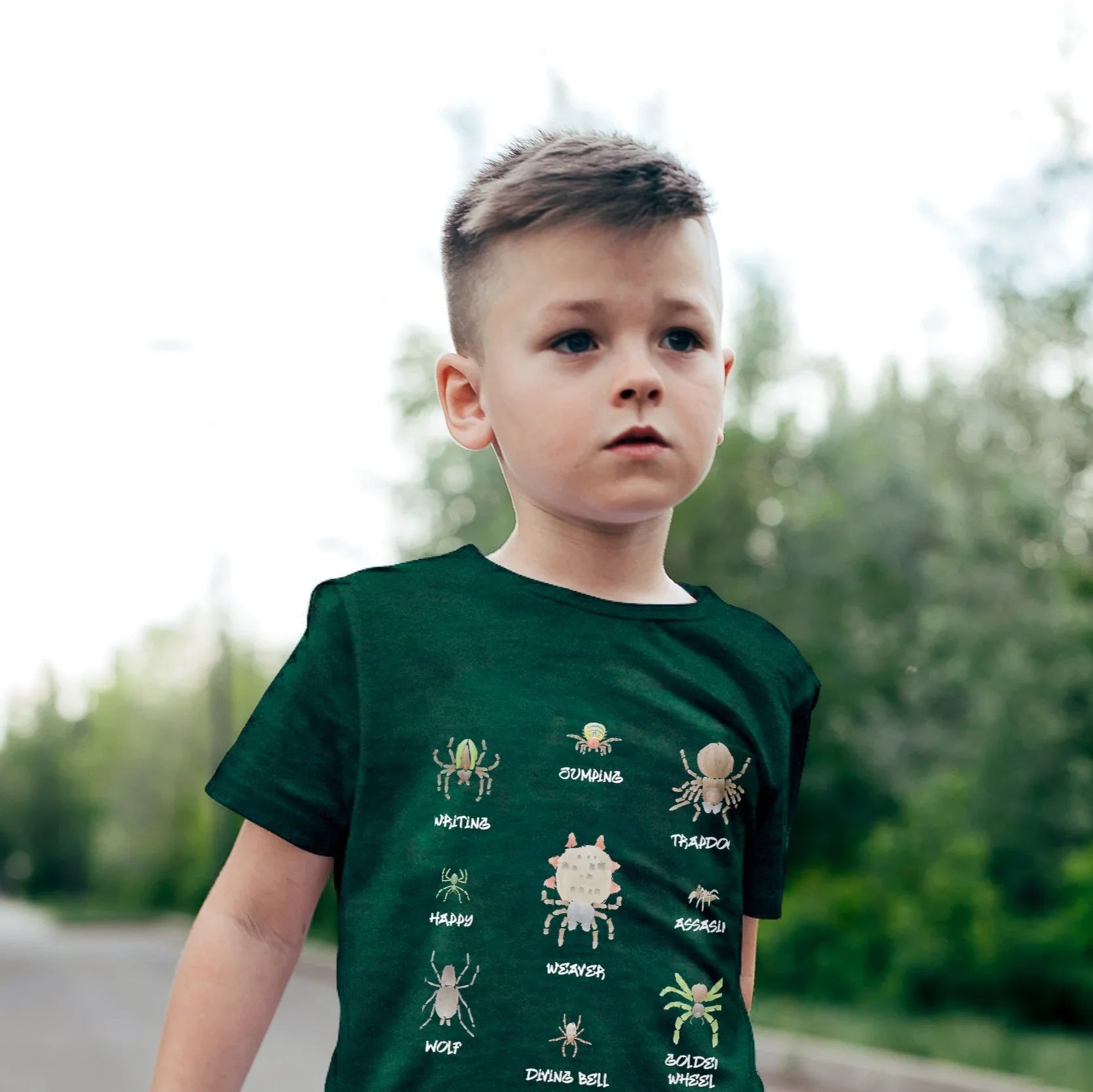 Child wearing a green Spider Collector House Panther t-shirt with insect illustrations outdoors
